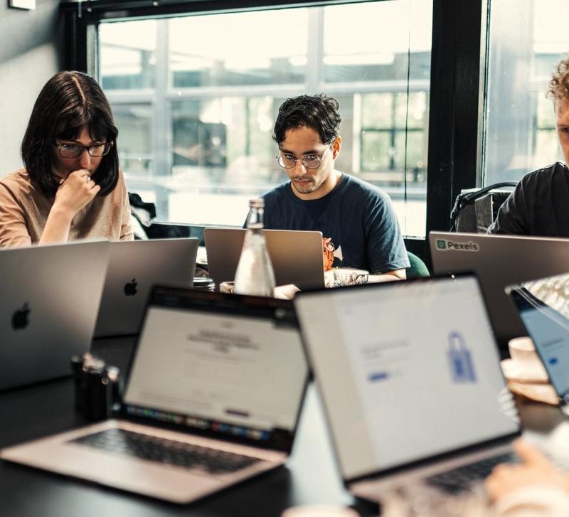 Business owners working on laptops together around one table