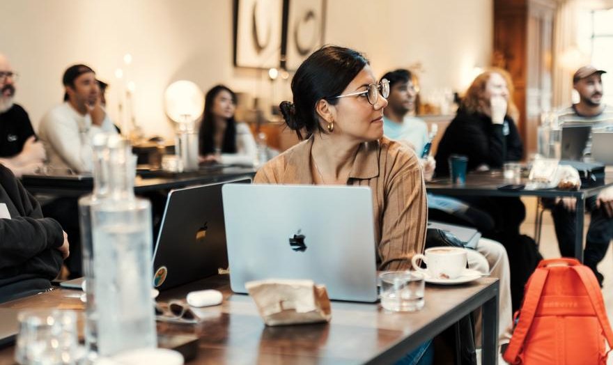 People at a workshop, laptops open, watching a demo at the front of the room
